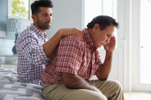 30something man with dark hair and beard places hand on shoulder of older man leaning over in front of him