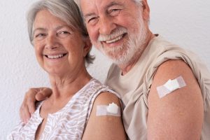 smiling senior couple show off bare arms with bandages
