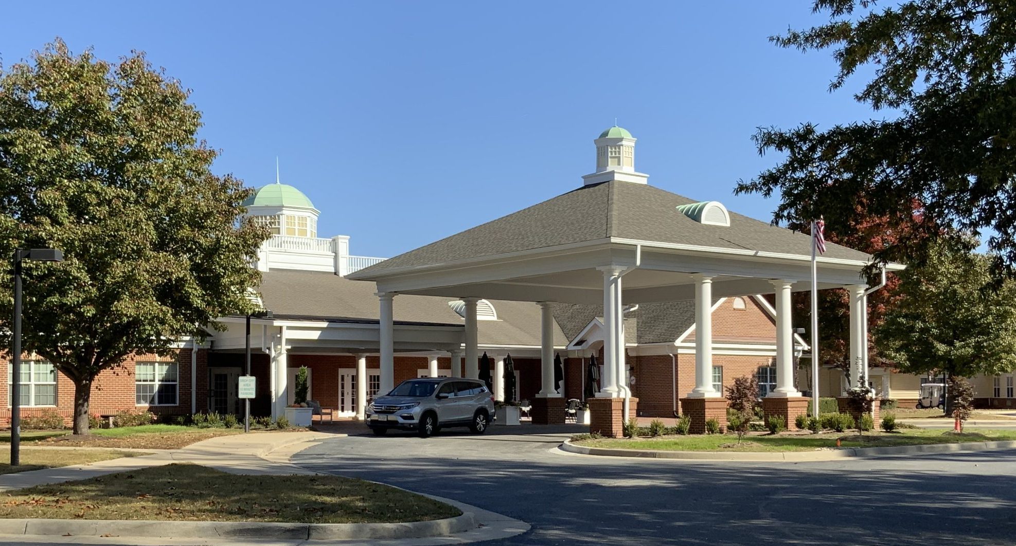 porte-cochere with white columns in front of brick buildign
